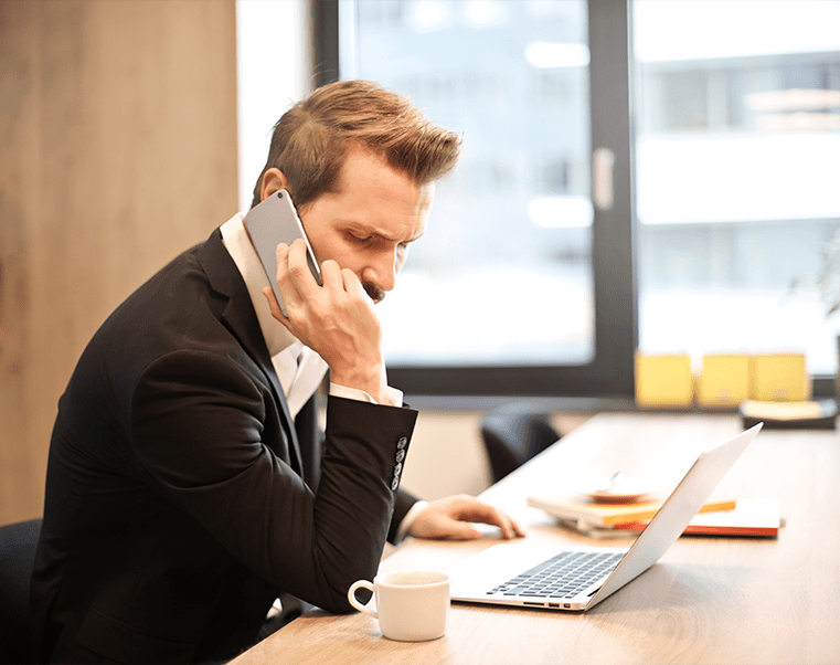 Un hommme parlant au téléphone travaillant sur un ordinateur